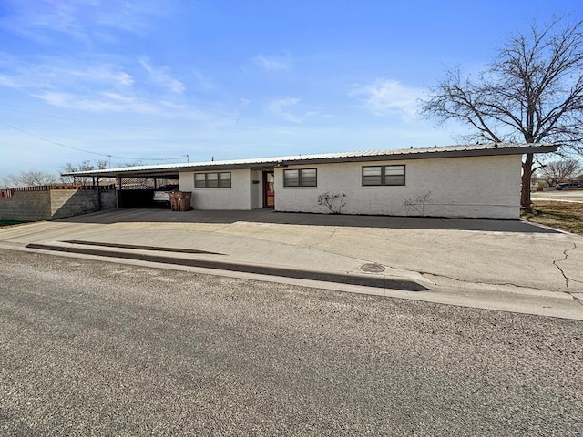 view of front of property featuring concrete driveway, an attached carport, and stucco siding