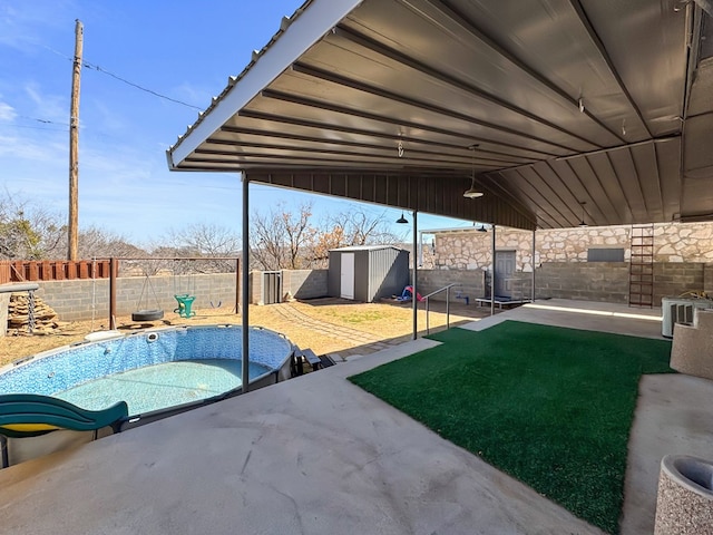 view of patio / terrace featuring a storage shed, an outbuilding, a fenced backyard, and a pool