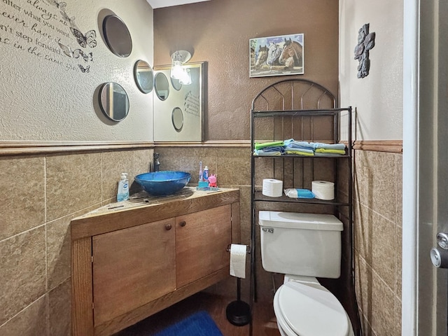 bathroom with a wainscoted wall, toilet, and tile walls