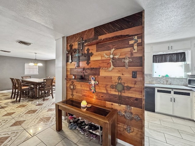 kitchen with light countertops, visible vents, white cabinets, a textured ceiling, and dishwasher