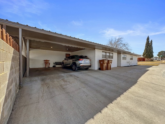 garage featuring fence, a carport, and concrete driveway