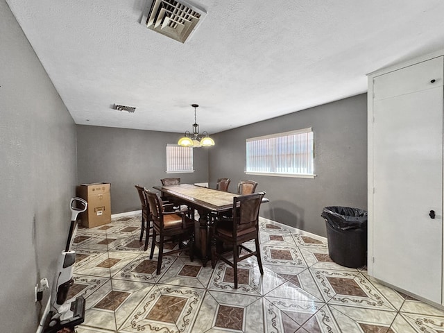 dining area with a textured ceiling, baseboards, visible vents, and a notable chandelier