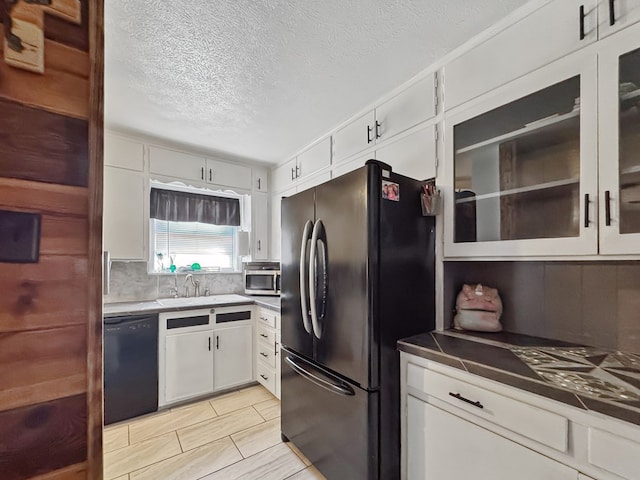 kitchen featuring a sink, white cabinetry, backsplash, black appliances, and glass insert cabinets