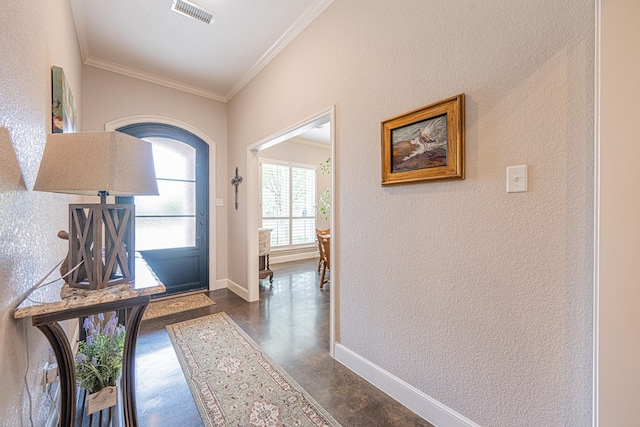 entrance foyer featuring ornamental molding, baseboards, a textured wall, and finished concrete floors