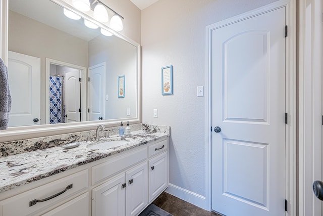 bathroom with vanity, baseboards, and a textured wall