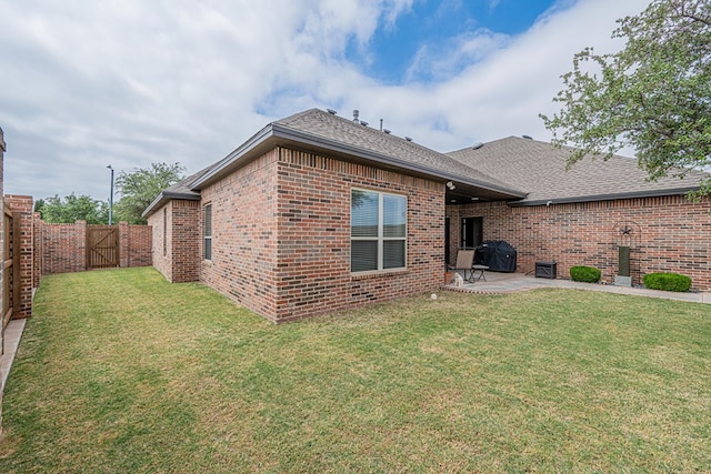 rear view of property with brick siding, a patio area, a shingled roof, and a gate