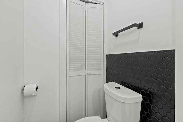 bathroom with tile walls and toilet