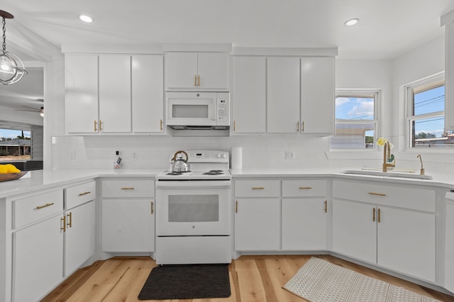 kitchen featuring white cabinets, decorative light fixtures, a healthy amount of sunlight, and white appliances