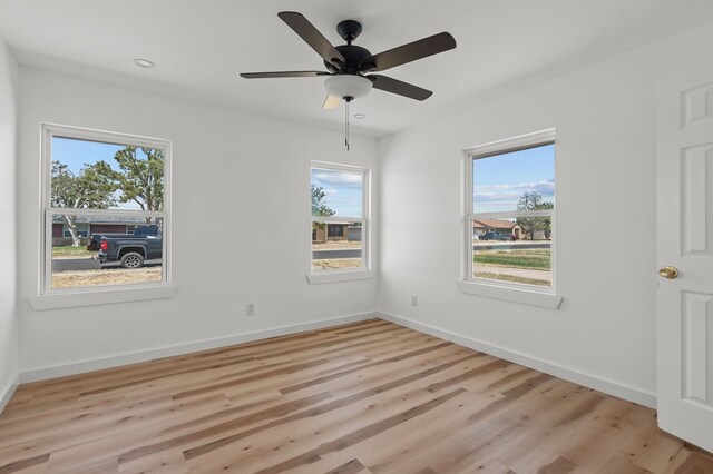 spare room with light hardwood / wood-style floors, ceiling fan, and a healthy amount of sunlight