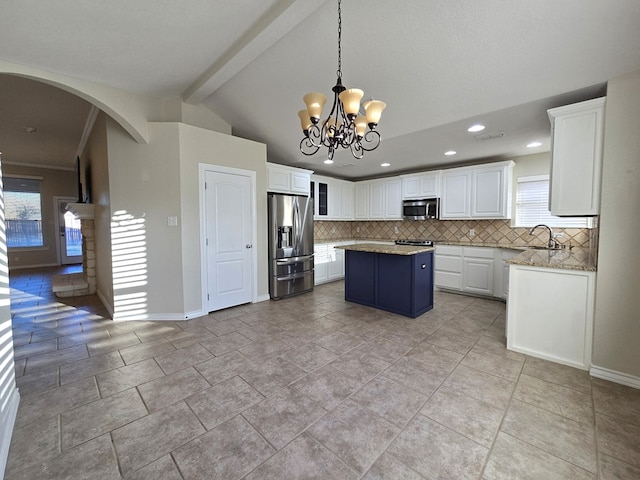 kitchen featuring arched walkways, a center island, stainless steel appliances, white cabinetry, and tasteful backsplash