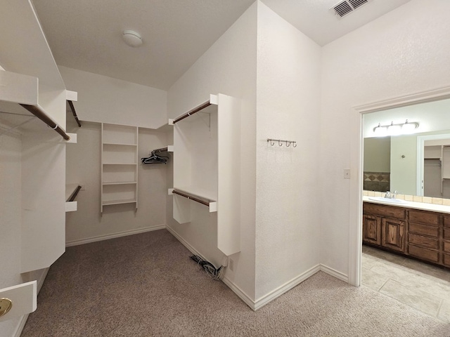 walk in closet featuring visible vents, a sink, and light carpet