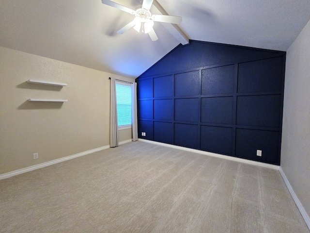 spare room with a ceiling fan, lofted ceiling with beams, a decorative wall, and carpet flooring