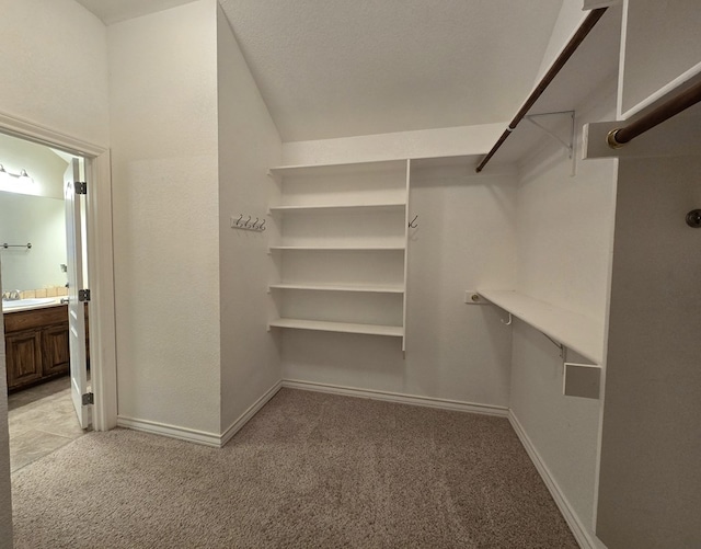 walk in closet featuring light colored carpet and a sink
