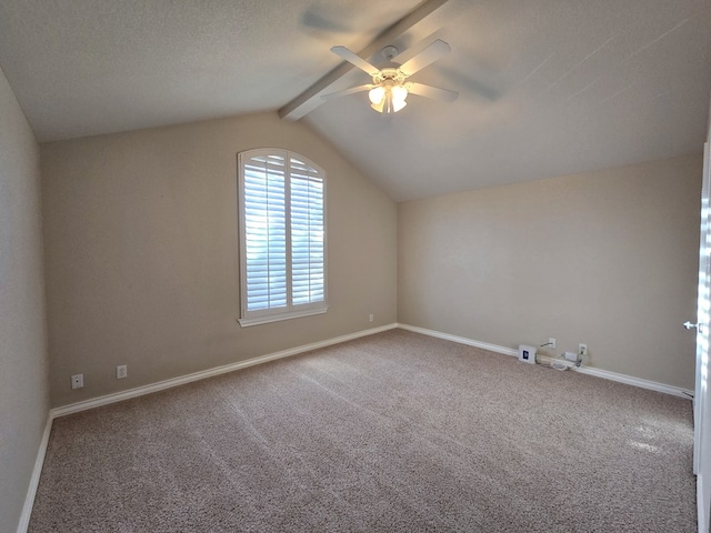 spare room featuring carpet floors, vaulted ceiling with beams, baseboards, and a ceiling fan