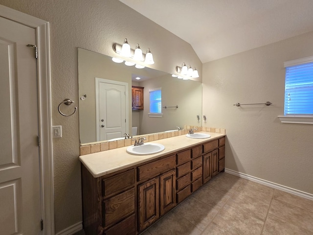 bathroom featuring double vanity, tile patterned floors, a sink, and lofted ceiling