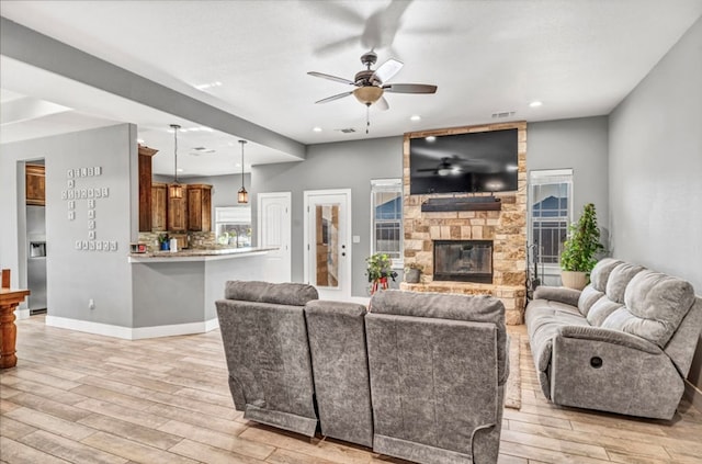 living room with ceiling fan, a fireplace, and light hardwood / wood-style flooring