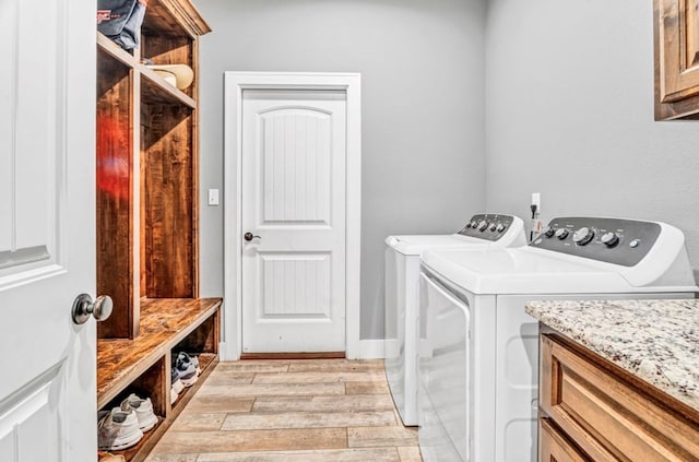 clothes washing area featuring cabinets, washer and dryer, and light hardwood / wood-style floors