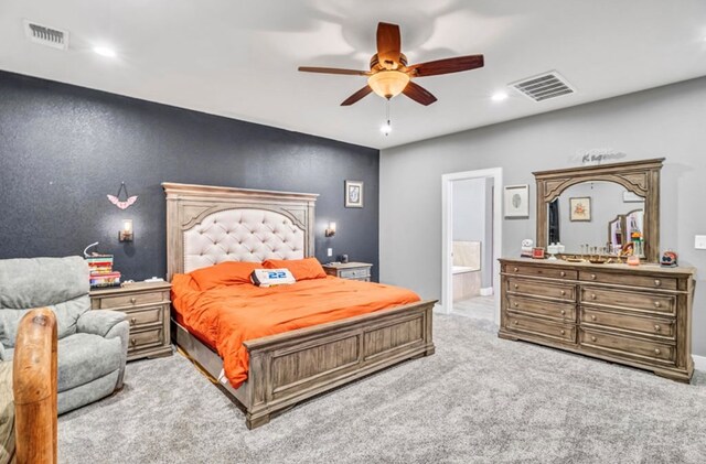 bedroom featuring ceiling fan, light colored carpet, and ensuite bath