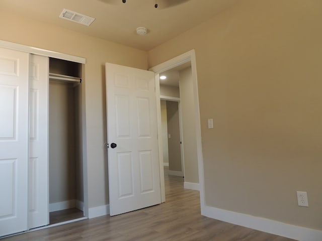 unfurnished bedroom featuring wood-type flooring and a closet