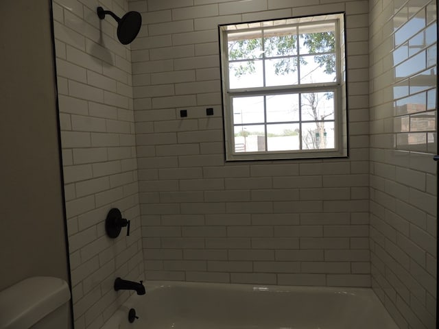 bathroom featuring tiled shower / bath combo, plenty of natural light, and toilet