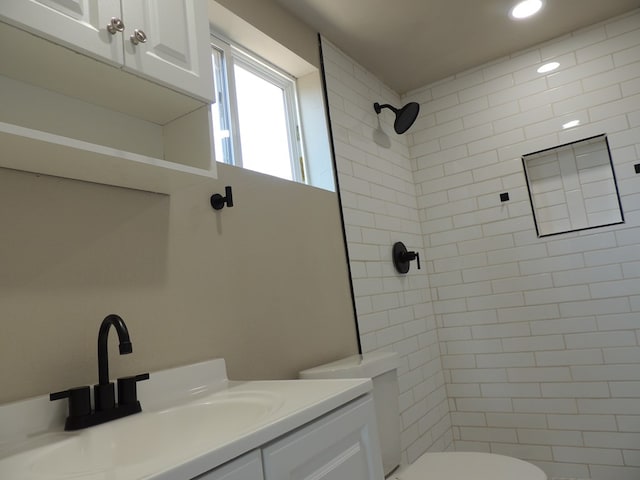 bathroom with vanity, toilet, and a tile shower