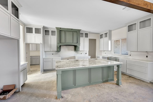 kitchen with a kitchen island, a kitchen bar, ornamental molding, and light stone countertops