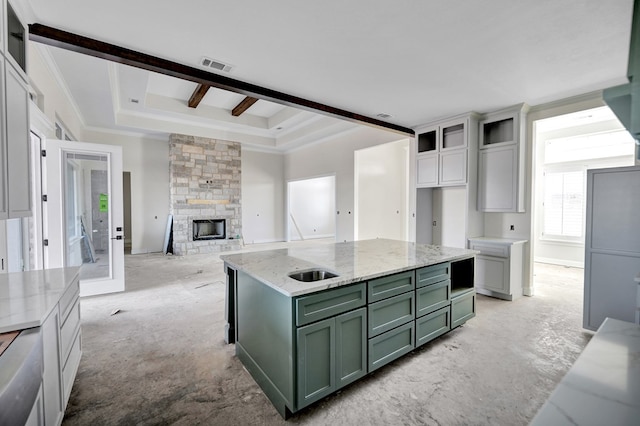 kitchen with green cabinetry, white cabinetry, light stone counters, a raised ceiling, and a stone fireplace