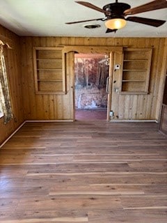 unfurnished room featuring hardwood / wood-style flooring, built in shelves, and wood walls