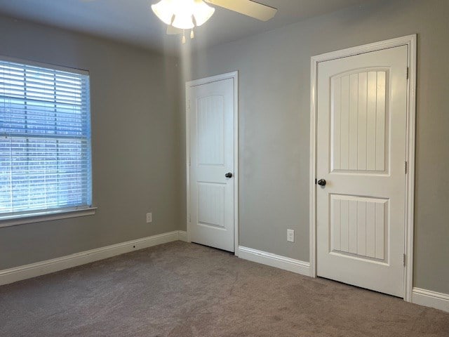 unfurnished bedroom featuring carpet floors, multiple windows, and baseboards