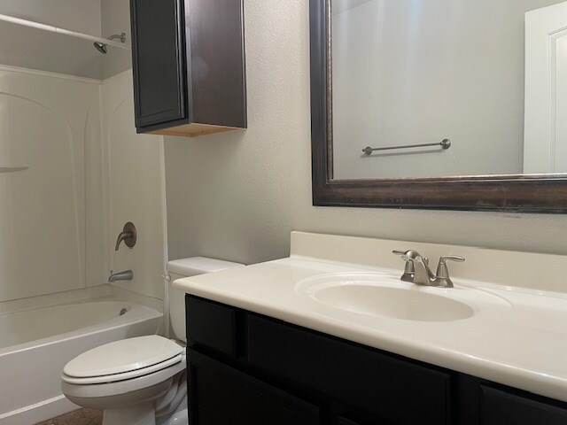 bathroom with shower / bathing tub combination, vanity, and toilet