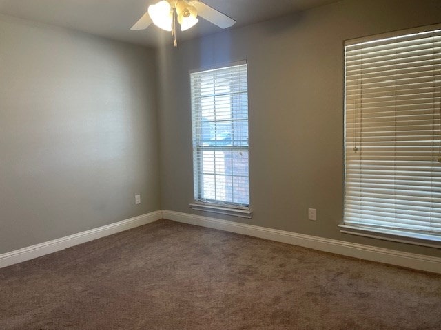 carpeted empty room with a ceiling fan and baseboards