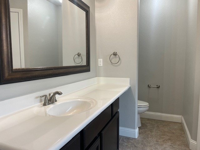 bathroom with baseboards, vanity, and toilet