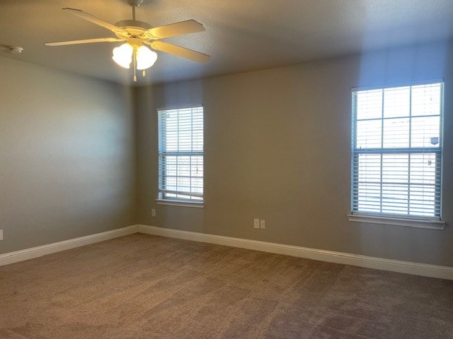 carpeted empty room with baseboards and a ceiling fan