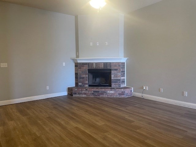 unfurnished living room featuring a fireplace, wood finished floors, and baseboards