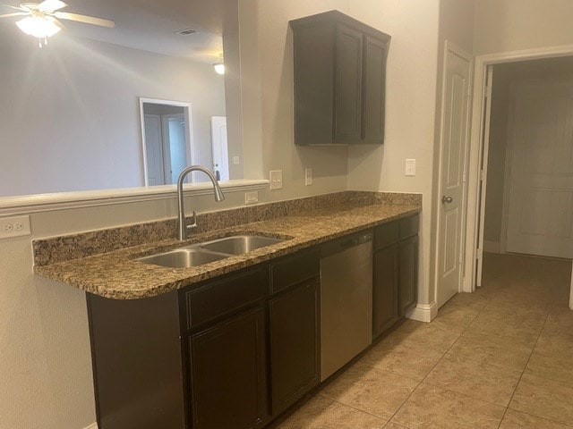 kitchen with light tile patterned floors, dark stone counters, ceiling fan, stainless steel dishwasher, and a sink