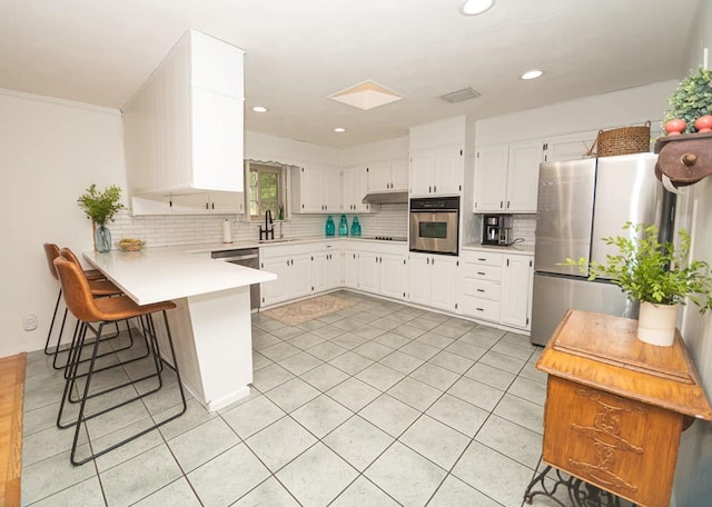 2718 Central Ave, Big Spring, TX 79720 - kitchen with stainless steel appliances, a peninsula, backsplash, light countertops, and white cabinets