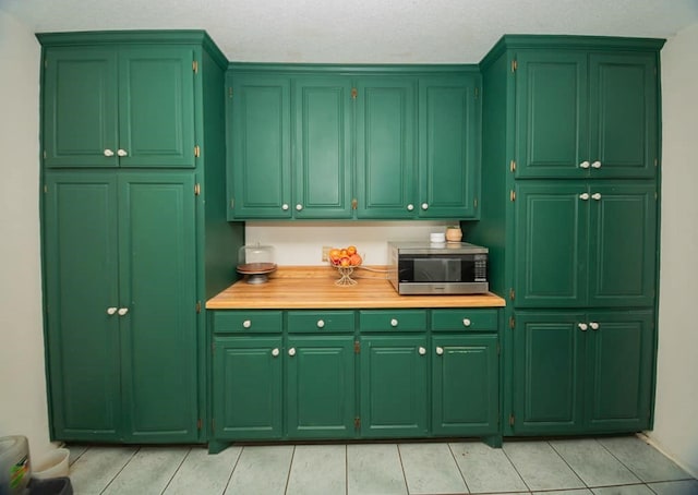 2718 Central Ave, Big Spring, TX 79720 - kitchen with stainless steel microwave, light tile patterned floors, green cabinets, and light countertops