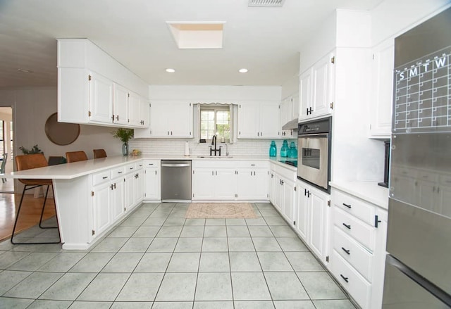 2718 Central Ave, Big Spring, TX 79720 - kitchen with stainless steel appliances, a peninsula, light tile patterned floors, decorative backsplash, and light countertops