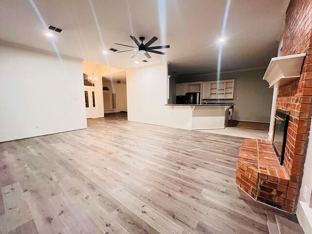 unfurnished living room featuring a fireplace, light hardwood / wood-style floors, and ceiling fan