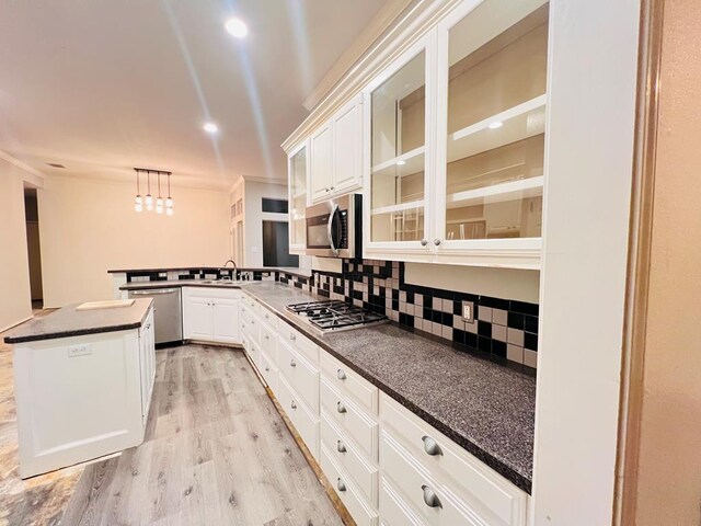 kitchen featuring light wood-type flooring, tasteful backsplash, stainless steel appliances, sink, and decorative light fixtures