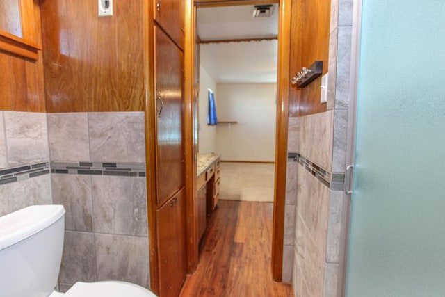 bathroom featuring walk in shower, hardwood / wood-style floors, tile walls, and toilet