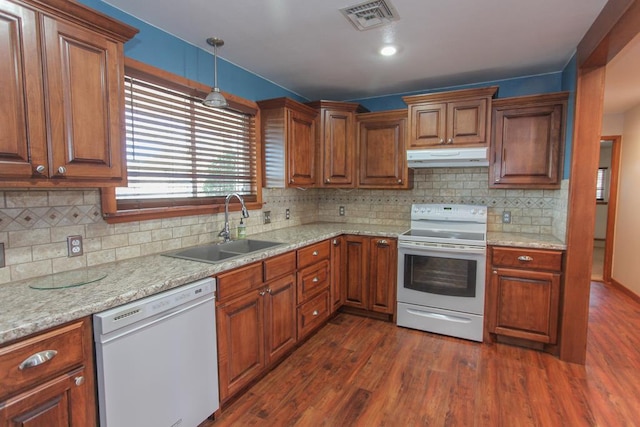 kitchen featuring light stone countertops, sink, hanging light fixtures, dark hardwood / wood-style flooring, and white appliances