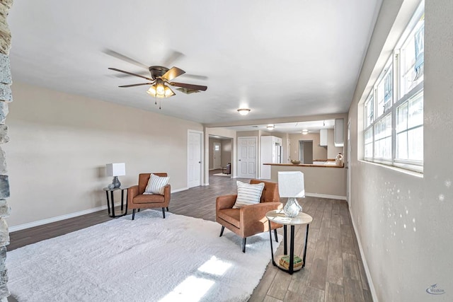 sitting room with wood finished floors, a ceiling fan, and baseboards