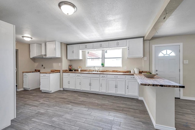 kitchen with butcher block counters, wood tiled floor, and white cabinetry