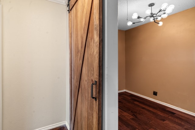 interior space with hardwood / wood-style floors, a barn door, a textured ceiling, and an inviting chandelier