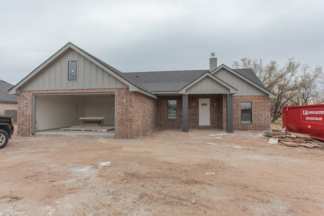 view of front of property with a garage, a chimney, and brick siding