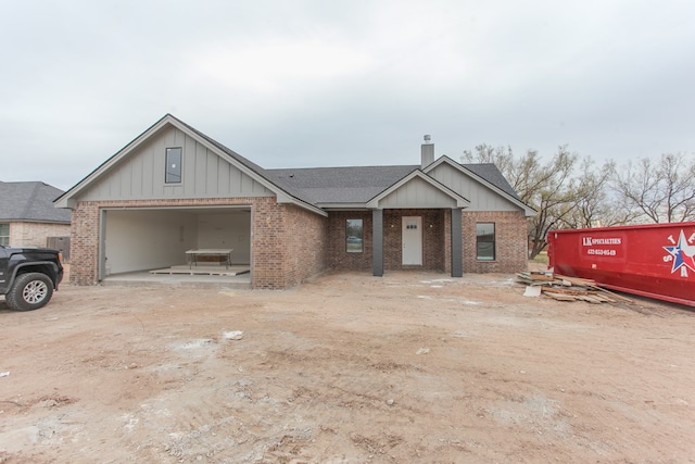 view of front facade with driveway, brick siding, a chimney, and an attached garage