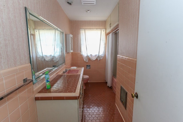 1706 Harvard Ave, Big Spring, TX 79720 - bathroom with wallpapered walls, toilet, tile walls, tile patterned flooring, and vanity