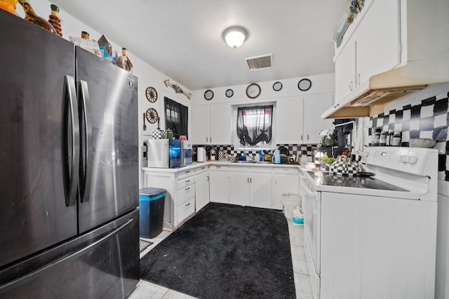 1606 Johnson St, Big Spring, TX 79720 - kitchen with freestanding refrigerator, white range with electric stovetop, tasteful backsplash, and white cabinetry