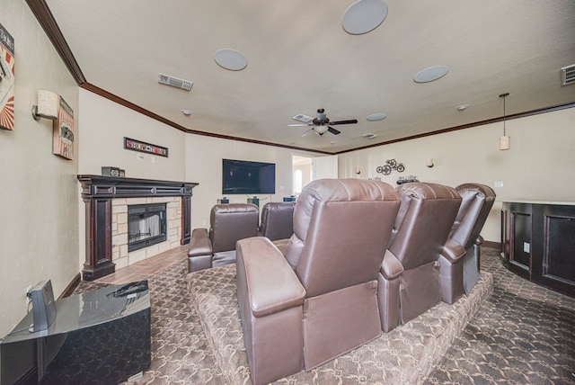 carpeted cinema room with a textured ceiling, ceiling fan, crown molding, and a fireplace